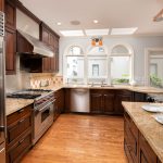 Luxe kitchen with granite countertops, ceramic backsplash, oak hardwood floors, skylights, an eating and serving bar.
